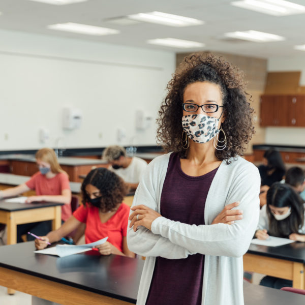 High school students and teenagers and teachers go back to school in the classroom at their high school. They are required to wear face masks and practice social distancing during the COVID-19 pandemic. They value their education and are excited to be in school.