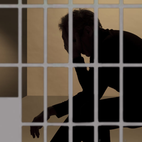 prisoner in prison, silhouette beyond the bars of the cell