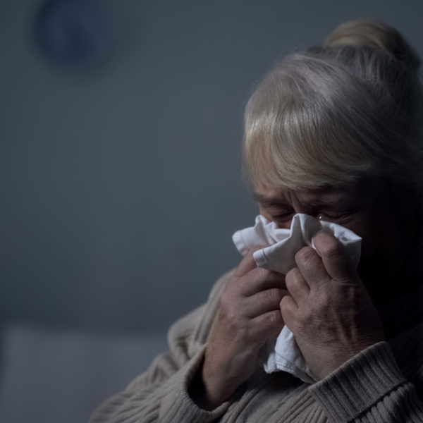 Desperate elderly female deeply crying in dark room, hospice loneliness, problem