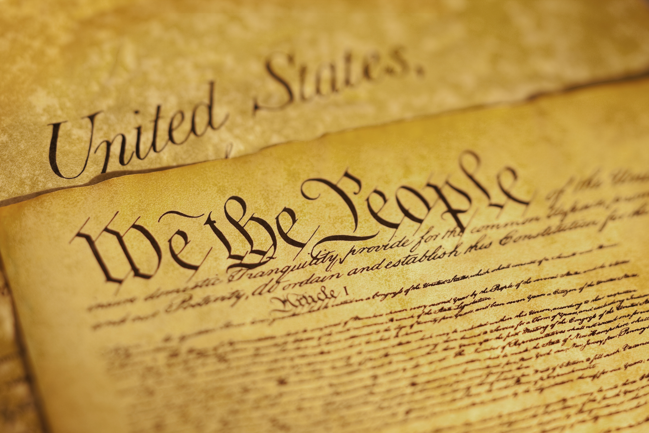 We the People are the opening words of the preamble to the Constitution of the USA. This image has a shallow depth of field to emphasize the opening phrase. The document underneath is a copy of the Bill of Rights.